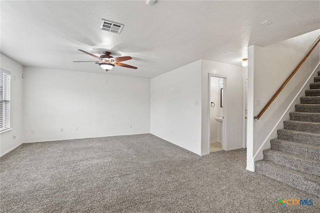 carpeted spare room featuring a textured ceiling and ceiling fan