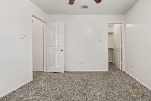 unfurnished bedroom featuring ceiling fan, carpet, a spacious closet, and a closet