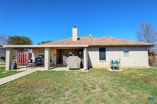 back of house with a patio area, a chimney, a yard, and brick siding