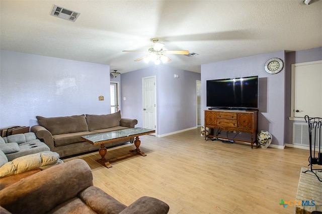 living area with visible vents, baseboards, a ceiling fan, and light wood finished floors