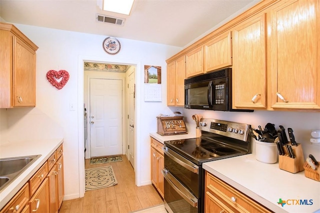 kitchen with light brown cabinets, visible vents, range with two ovens, a sink, and black microwave