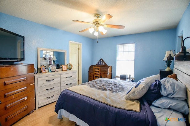 bedroom featuring a textured ceiling, a ceiling fan, and light wood-style floors