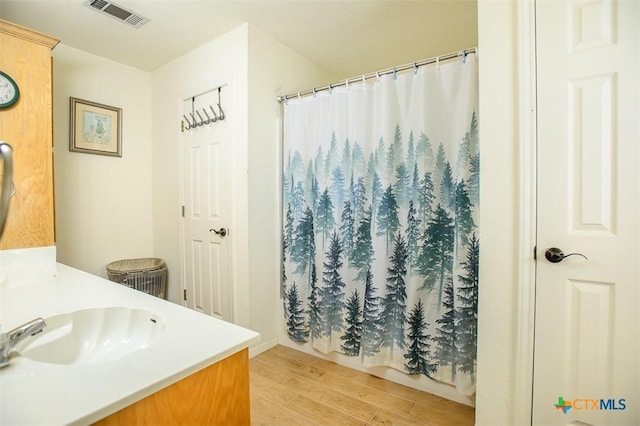 full bathroom featuring vanity, a shower with curtain, wood finished floors, and visible vents