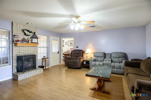 living room featuring plenty of natural light, wood finished floors, visible vents, and a textured ceiling