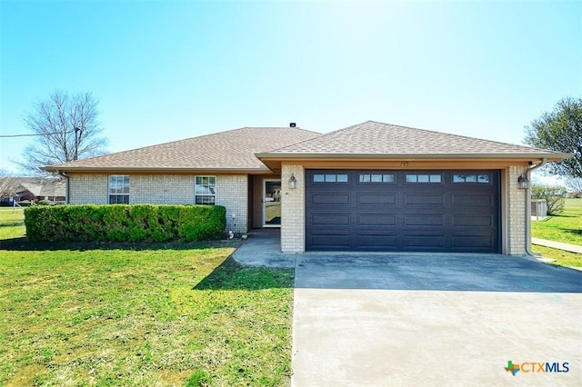 view of front of house featuring brick siding, an attached garage, concrete driveway, and a front yard