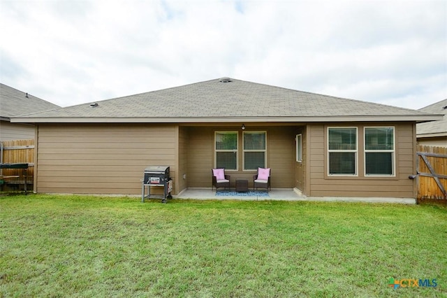rear view of property featuring a yard, roof with shingles, a fenced backyard, and a patio