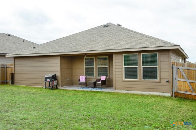 rear view of property with fence, a patio area, a shingled roof, and a yard