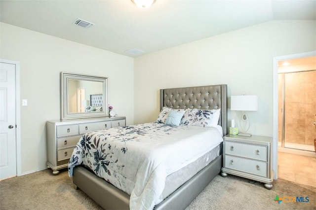 bedroom featuring light colored carpet, lofted ceiling, ensuite bath, and visible vents