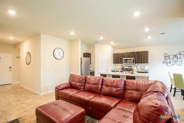 living area with baseboards, visible vents, and recessed lighting