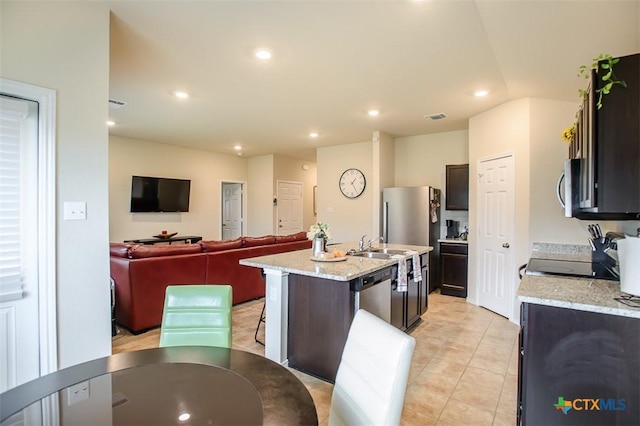 kitchen with stainless steel appliances, open floor plan, visible vents, an island with sink, and light tile patterned floors