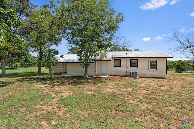 rear view of property featuring cooling unit and a yard