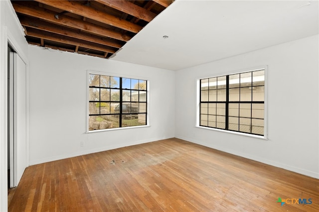 unfurnished room featuring beamed ceiling and light wood-type flooring