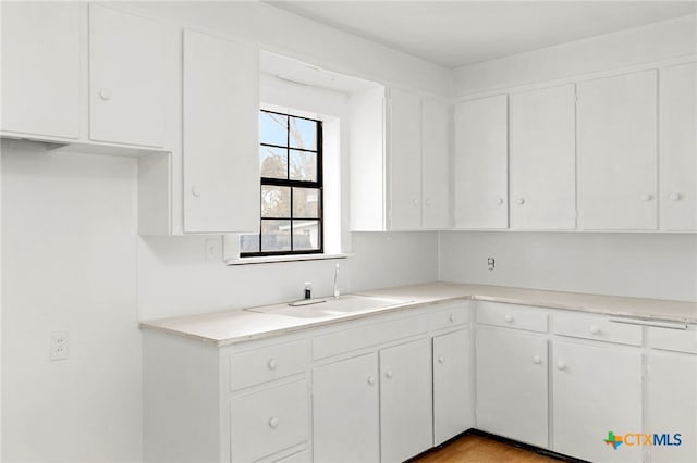 kitchen with white cabinetry, sink, and light hardwood / wood-style floors