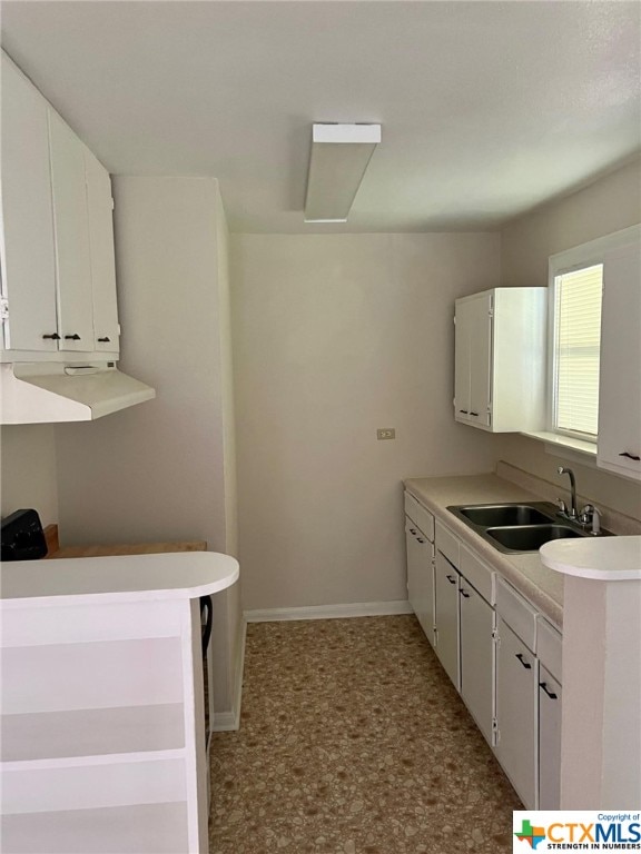 kitchen featuring white cabinets, sink, and kitchen peninsula