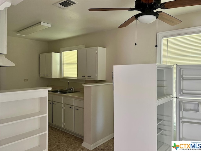 kitchen featuring white cabinetry, white refrigerator, sink, and ceiling fan