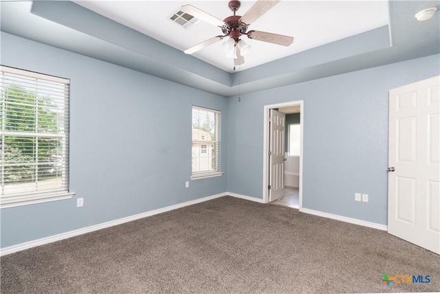 5204 Southern Crossing Dr, Temple, TX 76502 - unfurnished bedroom with dark carpet, a tray ceiling, baseboards, ensuite bathroom, and ceiling fan