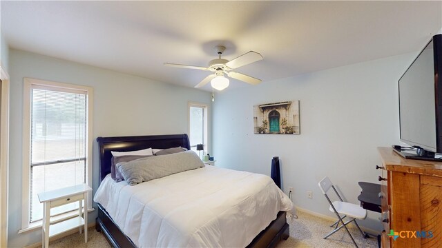 bedroom featuring ceiling fan, light colored carpet, and multiple windows