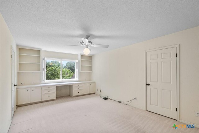 6013 Country Club Dr, Victoria, TX 77904 - unfurnished bedroom with built in study area, light colored carpet, a textured ceiling, and ceiling fan