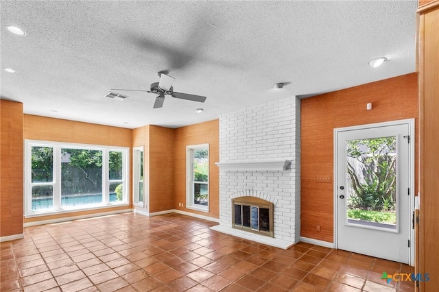 6013 Country Club Dr, Victoria, TX 77904 - unfurnished living room with a ceiling fan, plenty of natural light, a fireplace, a textured ceiling, and tile patterned flooring