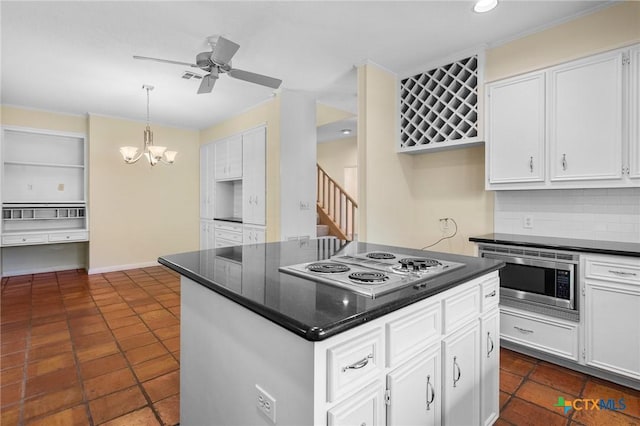 6013 Country Club Dr, Victoria, TX 77904 - kitchen with stainless steel microwave, ceiling fan, white cabinets, backsplash, and electric cooktop