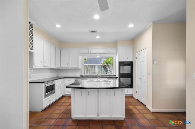 6013 Country Club Dr, Victoria, TX 77904 - kitchen with white cabinets, stainless steel microwave, backsplash, dark countertops, and recessed lighting