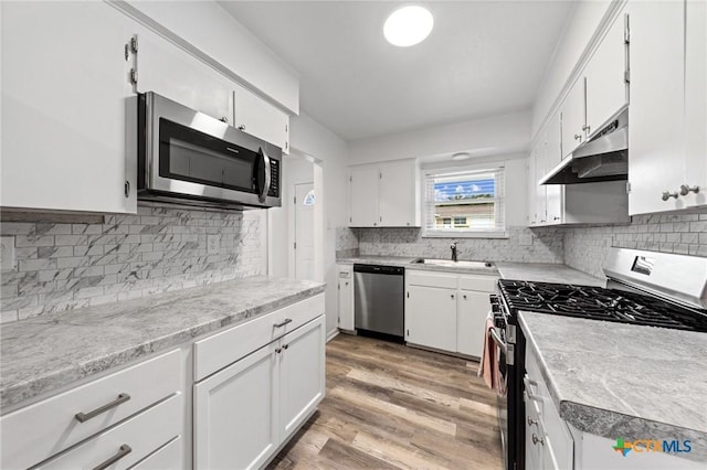 kitchen featuring sink, white cabinetry, backsplash, stainless steel appliances, and light hardwood / wood-style floors