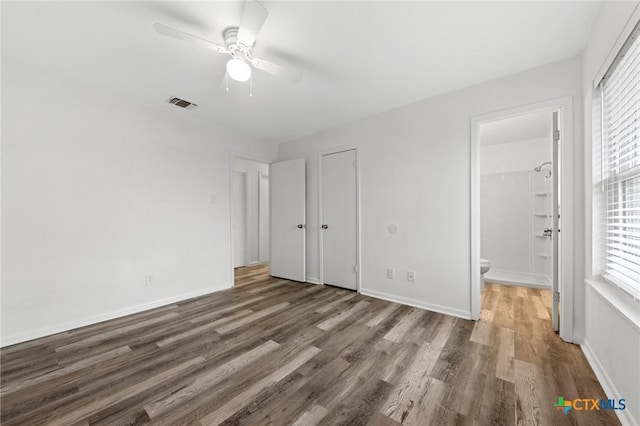 unfurnished bedroom with dark hardwood / wood-style floors, ceiling fan, and ensuite bathroom