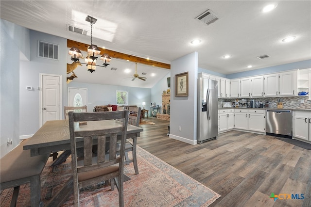 dining room featuring dark wood-type flooring, ceiling fan with notable chandelier, and lofted ceiling with beams