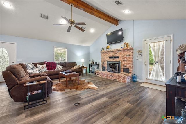 living room featuring dark wood-type flooring, plenty of natural light, beam ceiling, and a brick fireplace