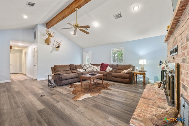 living room featuring high vaulted ceiling, a brick fireplace, hardwood / wood-style flooring, ceiling fan, and beam ceiling