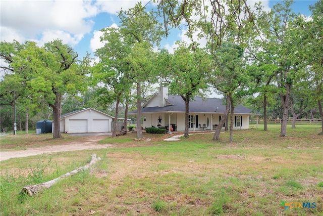 ranch-style home featuring an outbuilding, a garage, covered porch, and a front lawn