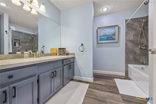 bathroom featuring hardwood / wood-style flooring, vanity, and tiled shower / bath combo