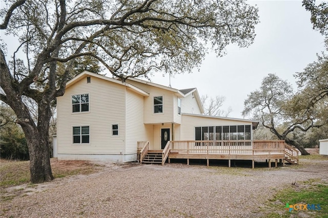 back of property with a deck and a sunroom