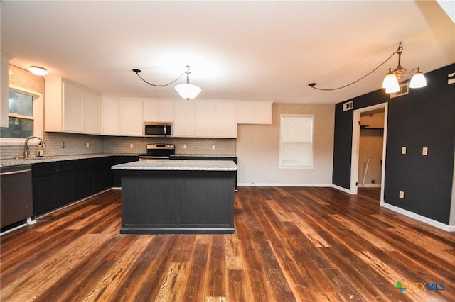 kitchen with white cabinetry, stainless steel appliances, a kitchen island, and pendant lighting