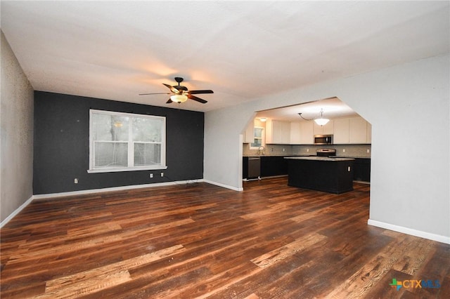 unfurnished living room featuring ceiling fan and dark hardwood / wood-style floors