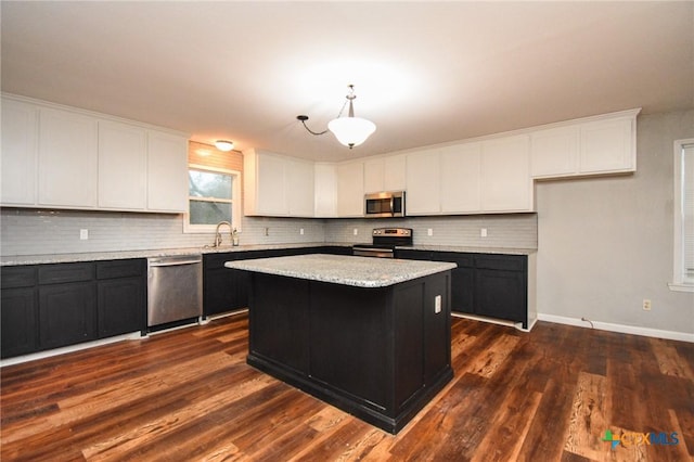 kitchen featuring sink, a center island, white cabinetry, decorative light fixtures, and stainless steel appliances