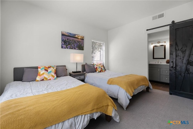 bedroom with visible vents, a barn door, carpet flooring, ensuite bath, and a sink