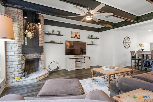 living room featuring beamed ceiling, wood finished floors, baseboards, and a large fireplace