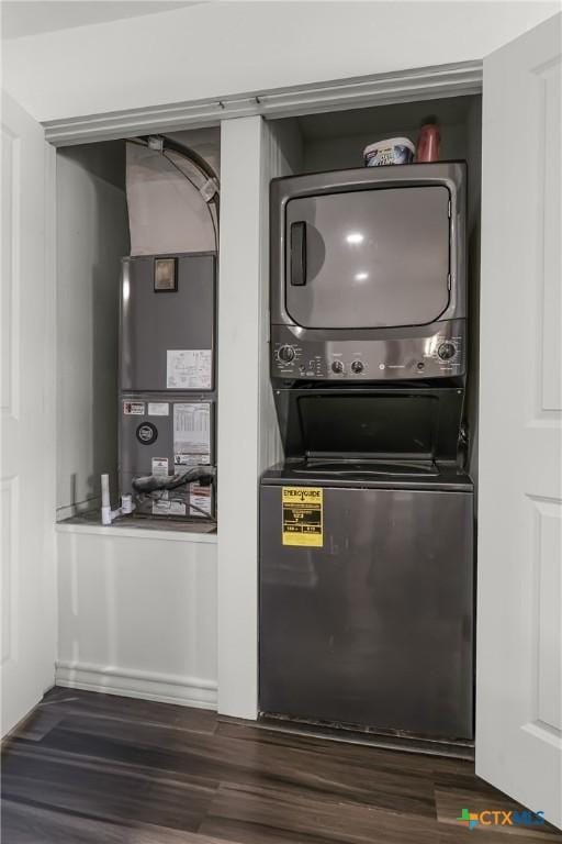 kitchen featuring heating unit, stacked washer and clothes dryer, and dark wood-style flooring