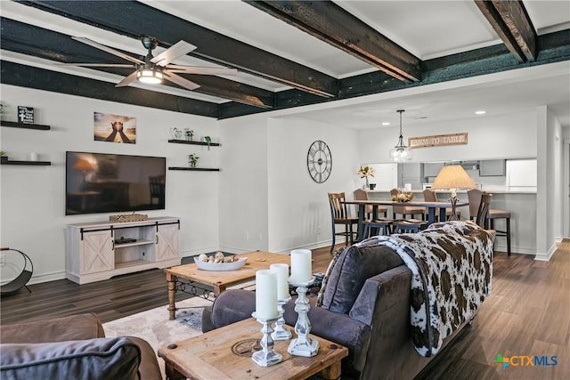 living area featuring ceiling fan, baseboards, beam ceiling, and wood finished floors