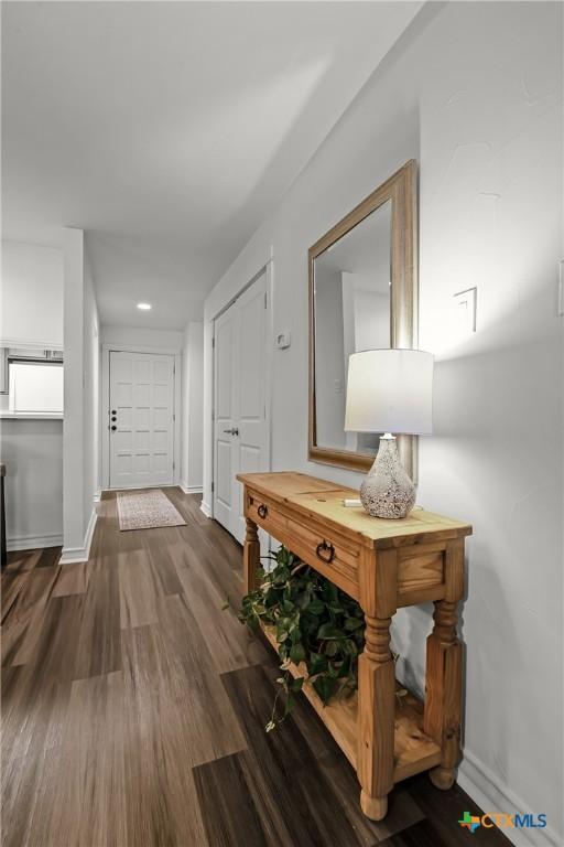 corridor with baseboards and wood finished floors