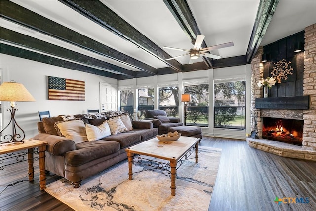 living area featuring a fireplace, beam ceiling, wood finished floors, and ceiling fan