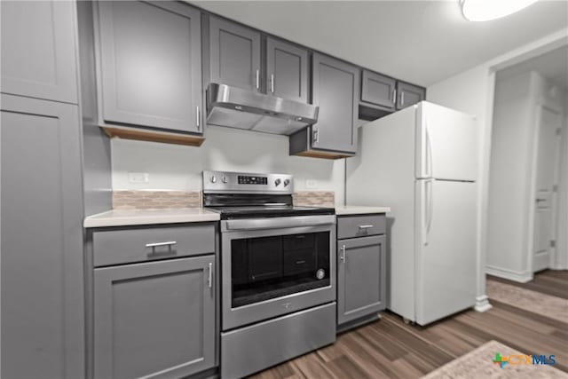 kitchen with under cabinet range hood, light countertops, gray cabinets, stainless steel electric range, and freestanding refrigerator