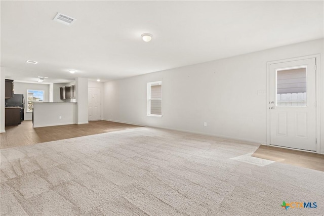 unfurnished living room featuring light colored carpet