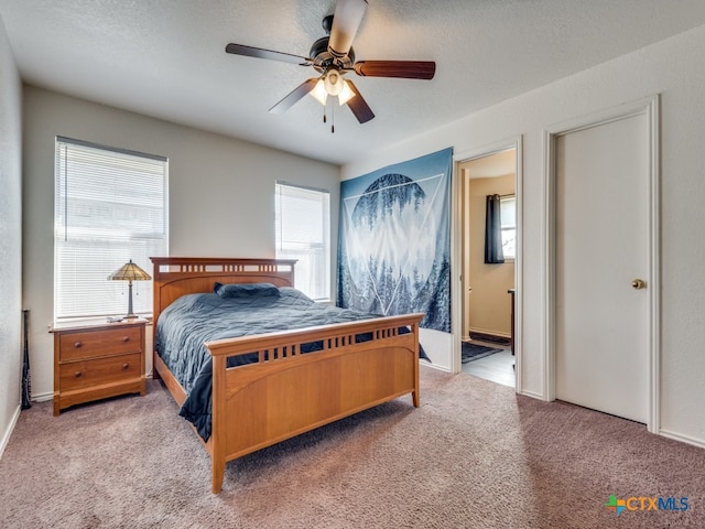 bedroom featuring ceiling fan, ensuite bath, a textured ceiling, and carpet