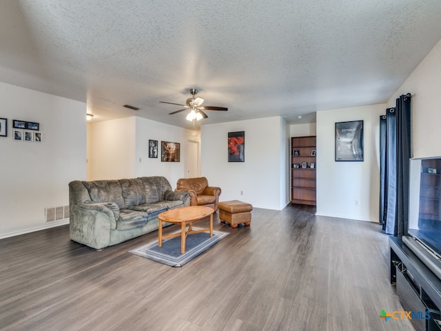 living room featuring a textured ceiling, dark hardwood / wood-style flooring, and ceiling fan