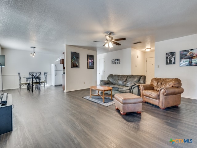 living room with dark wood-type flooring, a textured ceiling, and ceiling fan