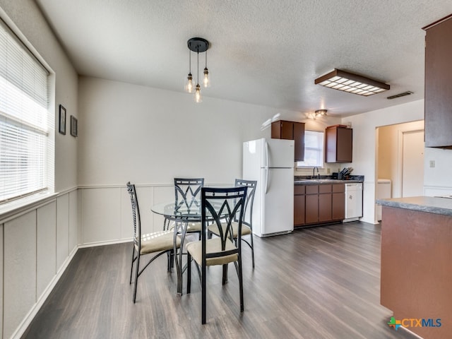 dining space featuring a wealth of natural light, a textured ceiling, sink, and dark hardwood / wood-style flooring