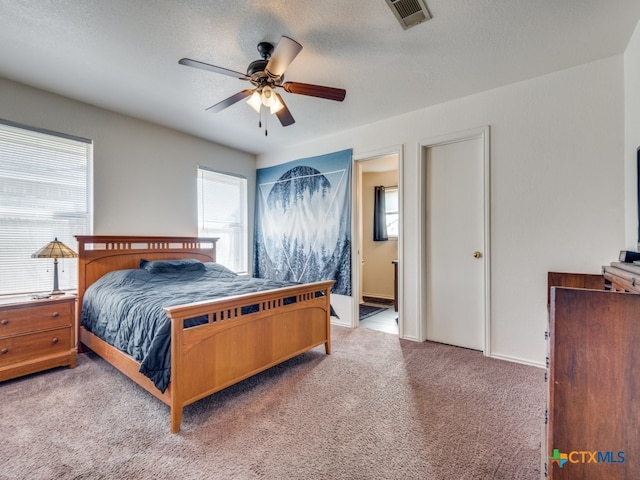 carpeted bedroom with ceiling fan, connected bathroom, and a textured ceiling