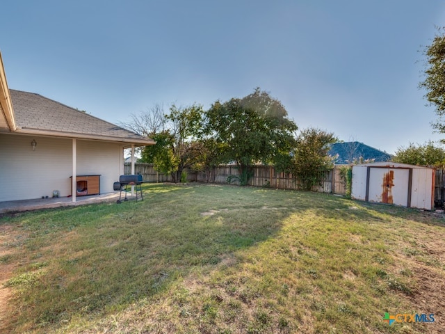 view of yard with a patio, a mountain view, and a storage shed